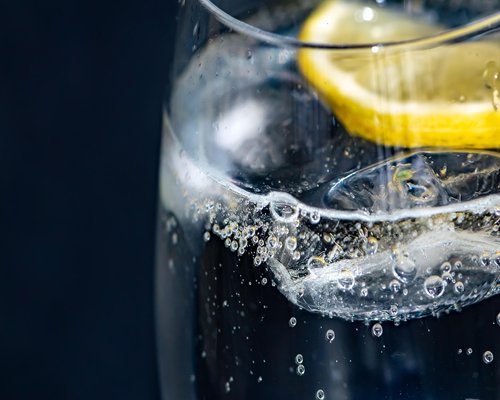 Glass of water with lemon slices next to a notebook